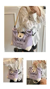Detail of purple canvas tote bag with embroidered letters and checkered woven handle