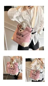 Detail of pink and beige canvas tote bag featuring black embroidery and woven handle
