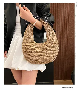Detail of straw woven half-moon handbag featuring a stylish polka dot silk scarf handle