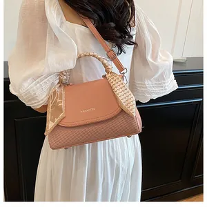 Pink crossbody bag detail with woven texture and silk scarf wrapped handle on white dress