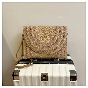 Detailed close-up of natural straw envelope clutch with unique layered texture and wristlet