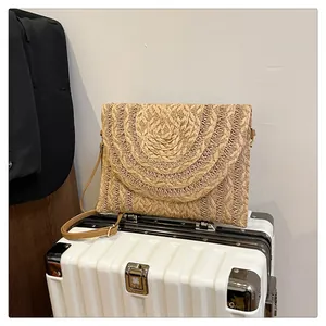 Detail of bohemian straw envelope bag with unique semi-circle woven texture and leather strap