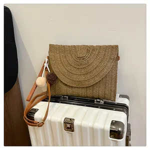 Detailed straw envelope bag showing woven semi-circular texture and leather strap
