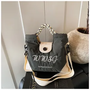 Detail of olive green nylon tote with woven checkered handle and adjustable strap