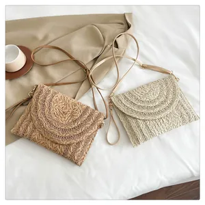 Detail of bohemian straw envelope bags in khaki and beige with woven texture and leather straps
