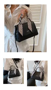 Detail of black woven texture handbag with fashion text and silk scarf handle
