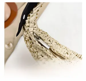 Macro detail of the smooth metal zipper and woven texture on a straw shoulder bag