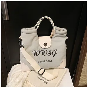 Detail of embroidered logo and checkered handle on this stylish cream tote bag