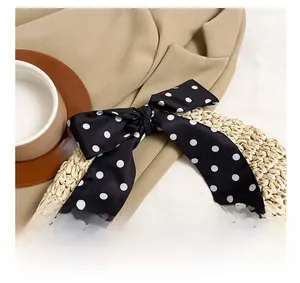Detail of straw woven handbag handle featuring a silk polka dot scarf bow decoration