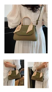 Close-up of retro green shoulder bag with silk scarf handle and woven texture detail