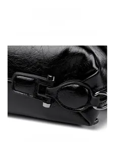 Close-up of polished black leather texture and gunmetal hardware latch on the handbag