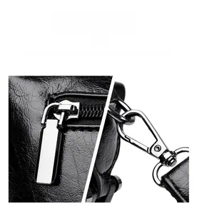 Detailed view of polished metal zipper and hardware on black leather shoulder bag