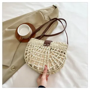 Detail van handgeweven strooien zadelitas met beige opengewerkt mesh en bruine leren riem
