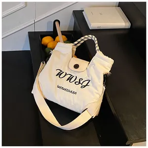 Macro detail of white canvas tote bag with contrast woven handles and logo print