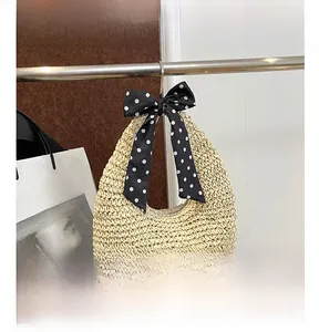Detail of straw hobo bag featuring a decorative black and white polka dot silk scarf