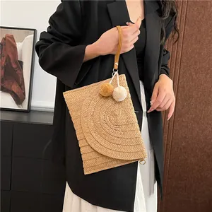 Beige straw woven envelope clutch with pom-pom charms and brown wrist strap for women