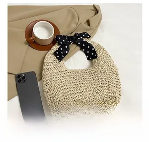 Detail view of a beige straw tote bag with a polka dot silk scarf handle and moon shape