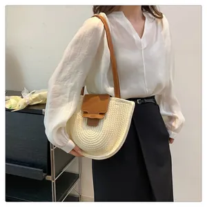 Detail der handgewebten Strohtasche mit brauner Lederklappe und verstellbarem Gurt