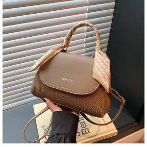 Detailed view of woven texture and silk scarf handle on brown fashion handbag