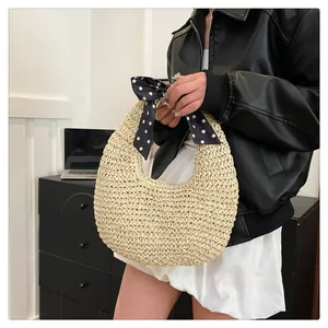 Detail of hand-woven straw hobo bag with a decorative polka dot silk scarf on handle