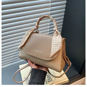 Detail of beige crossbody bag featuring woven texture and silk scarf wrapped handle