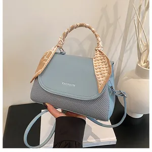 Close-up of light blue woven leather handbag with silk scarf handle and FASHION logo