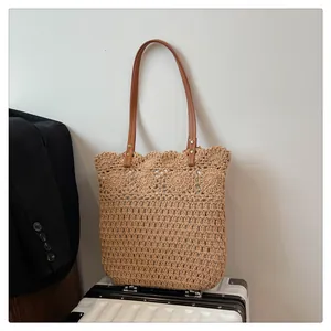 Detail der hohlen floralen Strickstruktur der beigen Strohtasche mit Lederriemen