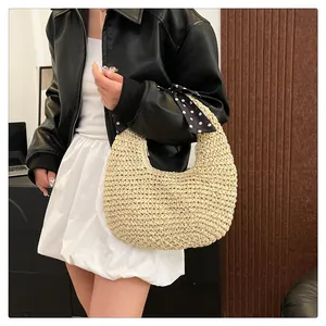 Detail of beige crescent woven handbag with a stylish black polka dot silk scarf handle