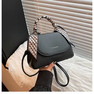 Detail of black crossbody bag featuring woven texture and silk scarf wrapped handle