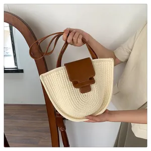 Detailansicht der gewebten Stroh-Schultertasche mit braunem Lederriemen und Schnalle