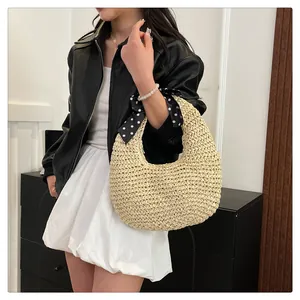 Detail of straw woven handbag featuring a black polka dot silk scarf on the handle