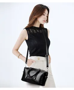 Detail of black pebbled leather handbag with adjustable strap and metallic logo accent