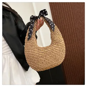Detail of light beige straw crescent bag with decorative polka dot silk scarf handle
