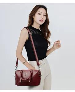Detail view of burgundy faux oil wax leather boston bag with metallic logo