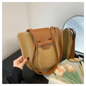 Detail der handgewebten Strohtasche mit brauner Lederklappe und Tulpendekoration