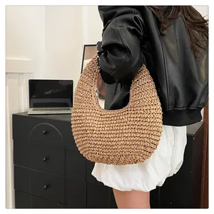 Detail of hand-woven straw hobo bag with khaki texture and metal zipper closure