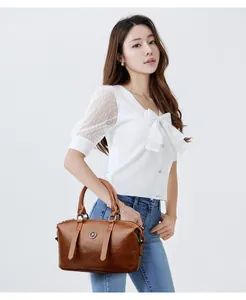 Chic brown leather handbag with metallic emblem worn with a casual white lace top