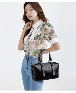 Detail of black faux leather handbag featuring a metallic kangaroo emblem and round design
