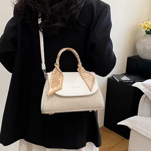 Chic beige crossbody bag with woven texture and silk scarf handle on model