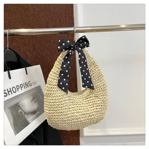 Detail view of woven straw shoulder bag with stylish black and white polka dot silk bow