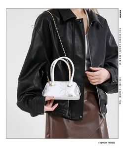 Detail shot of mini shell bag with white and silver snakeskin pattern and gold chain strap
