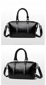 Detail of glossy black leather tote bag with round metal logo and detachable shoulder strap