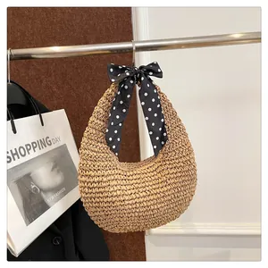 Detailed view of handmade woven straw hobo bag featuring a chic polka dot scarf on handle