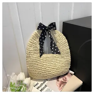 Close-up of beige woven straw handbag featuring a decorative black polka dot silk scarf