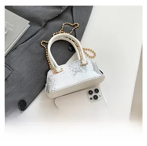 Mini shell bag with white snake-embossed leather, top handle, and chain shown next to phone