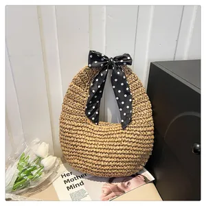 Detail of hand-woven straw hobo bag featuring a chic polka dot scarf on the handle