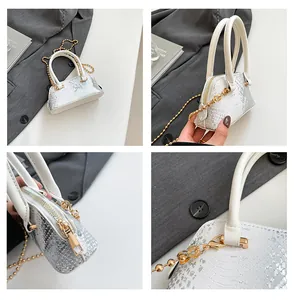 Detail view of silver snakeskin shell bag featuring gold chain strap and zipper hardware