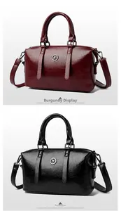 Detail view of burgundy and black soft leather shoulder bags with kangaroo metal emblem