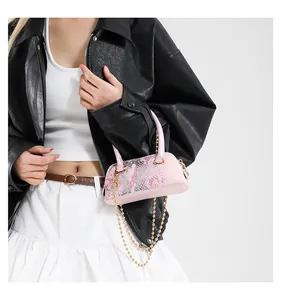 Detail of pink snake-print shell bag featuring golden chain strap and top handle
