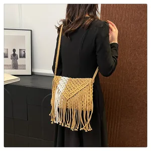 Detail of bohemian macrame fringe bag featuring a bicolor woven design with long tassels